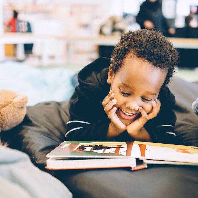 Niño sonriendo mientras lee un libro que de verdad le gusta