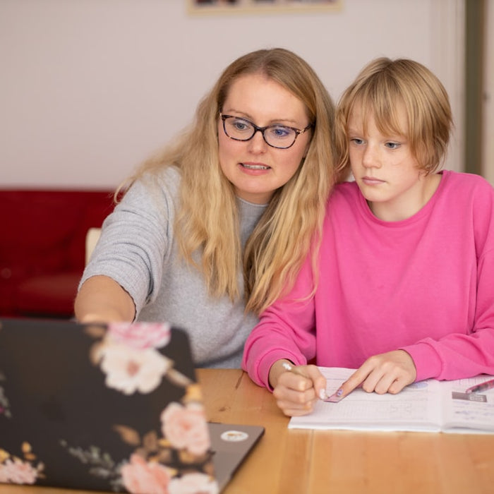 Madre ayudando a su hija a repasar tareas escolares en casa